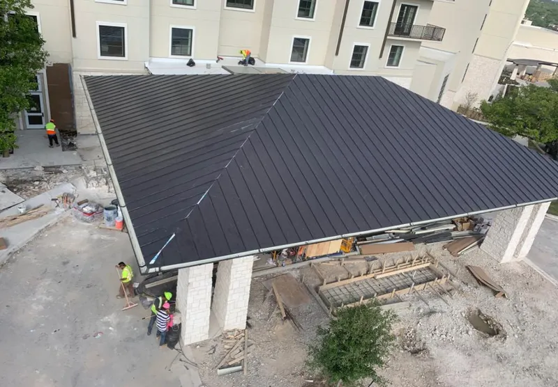 Metal roofing installation team working on a commercial building in Evergreen